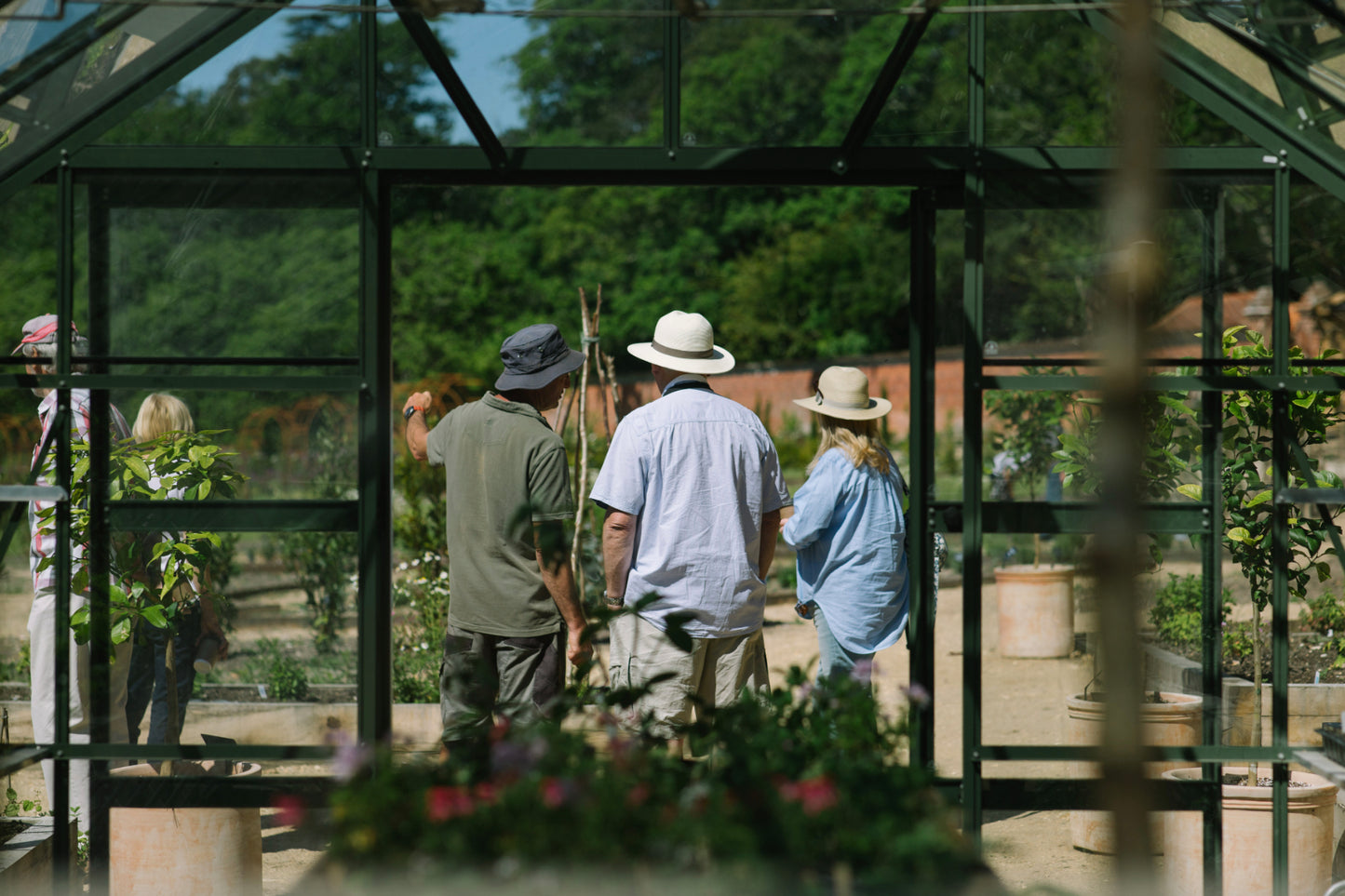 Visitors enjoying Carey’s Secret Garden on a sunny summer day, talking to the gardeners, relaxing in the vibrant garden, and soaking in the peaceful atmosphere.
