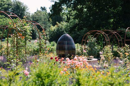 Carey’s Rose Wheel in full bloom, with vibrant roses surrounding a central water feature, creating a stunning focal point in the garden’s landscape