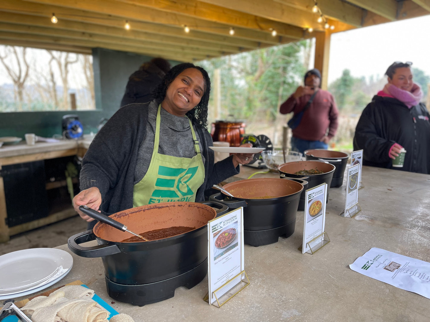 Chef serving delicious Ethiopian food from Carey’s outdoor kitchen, preparing vibrant, aromatic dishes in a beautiful open-air setting surrounded by nature.