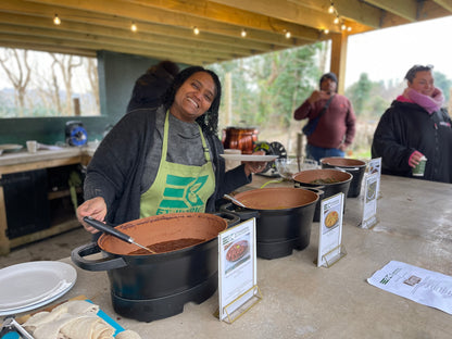 Chef serving delicious Ethiopian food from Carey’s outdoor kitchen, preparing vibrant, aromatic dishes in a beautiful open-air setting surrounded by nature.